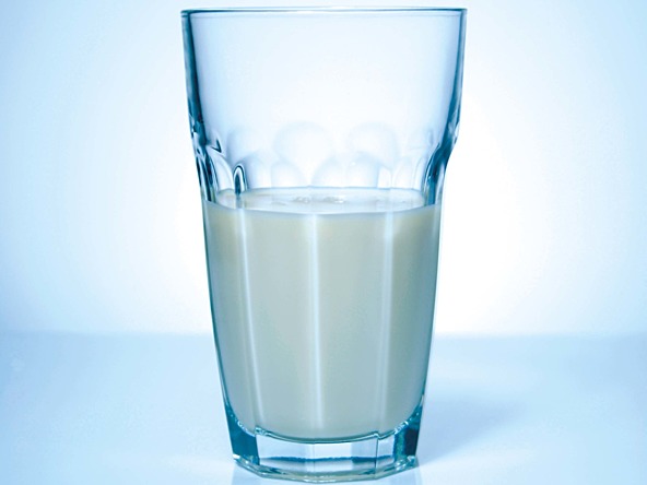 a half full glass on milk on a white background